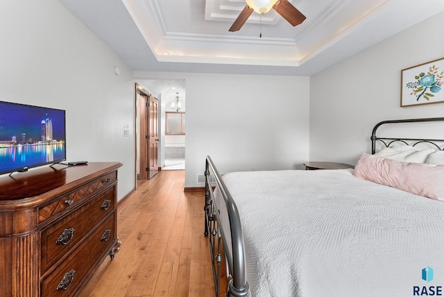 bedroom with ensuite bath, a tray ceiling, ceiling fan, and light hardwood / wood-style floors