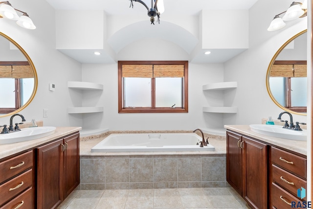 bathroom featuring plenty of natural light, a relaxing tiled tub, and vanity