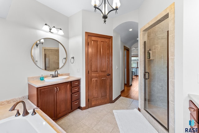 bathroom with hardwood / wood-style floors, separate shower and tub, a notable chandelier, and vanity