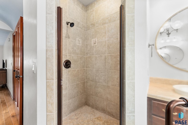 bathroom with a shower with shower door, hardwood / wood-style floors, and vanity