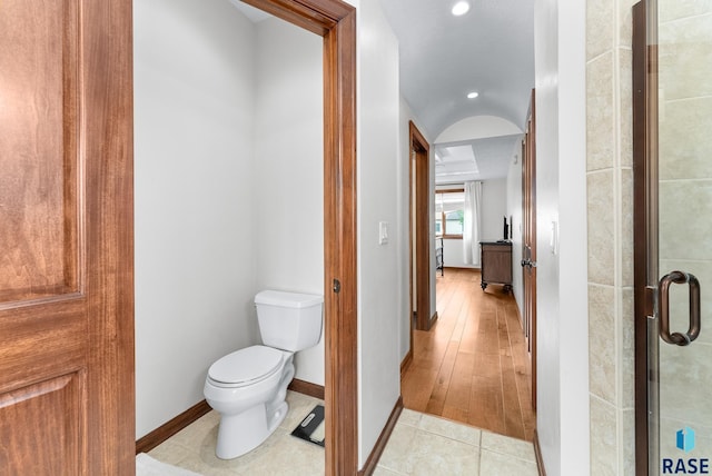 bathroom featuring toilet, wood-type flooring, and an enclosed shower