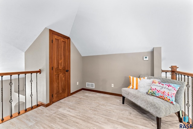 living area featuring light wood-type flooring and vaulted ceiling