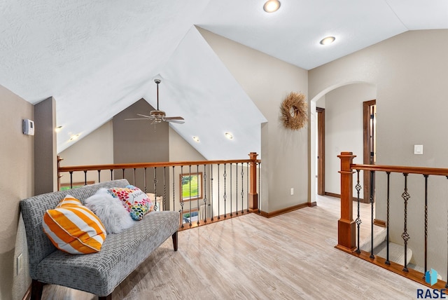 living area with lofted ceiling, light hardwood / wood-style flooring, ceiling fan, and a textured ceiling