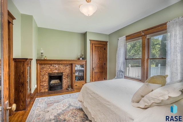 bedroom with wood-type flooring and a fireplace