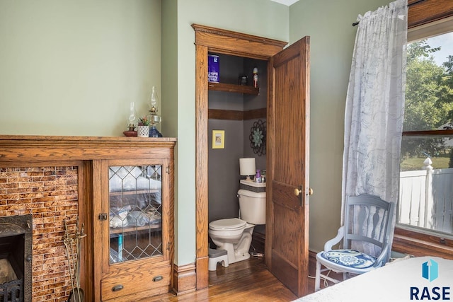 bathroom with hardwood / wood-style floors, a fireplace, and toilet