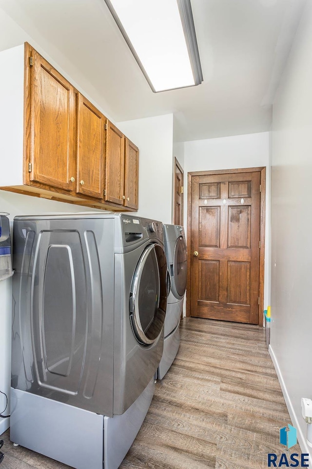 clothes washing area with cabinets and separate washer and dryer