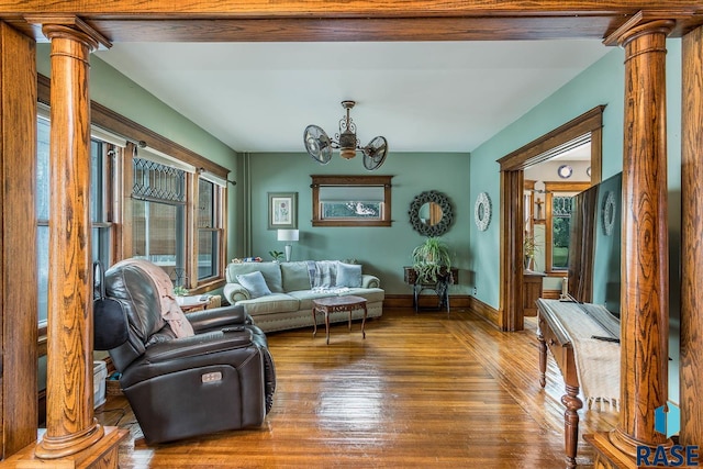 living room with a notable chandelier, decorative columns, and hardwood / wood-style floors