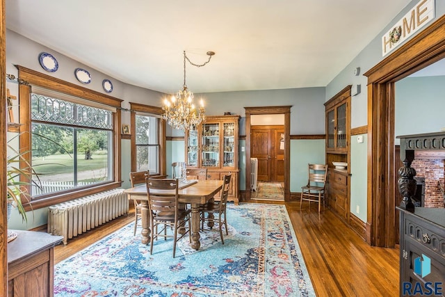 dining space featuring dark wood-type flooring, radiator heating unit, and a chandelier