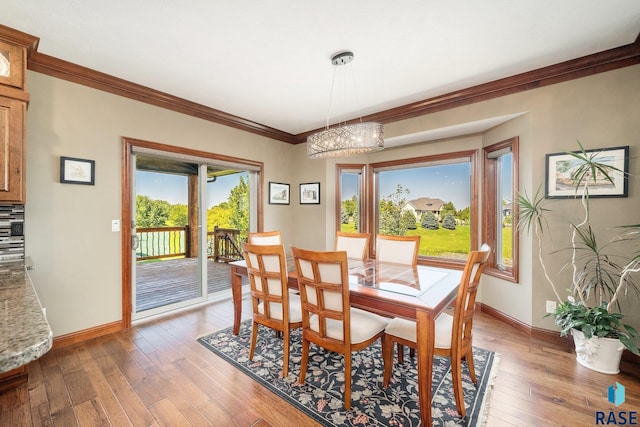 dining room with wood-type flooring, an inviting chandelier, and crown molding