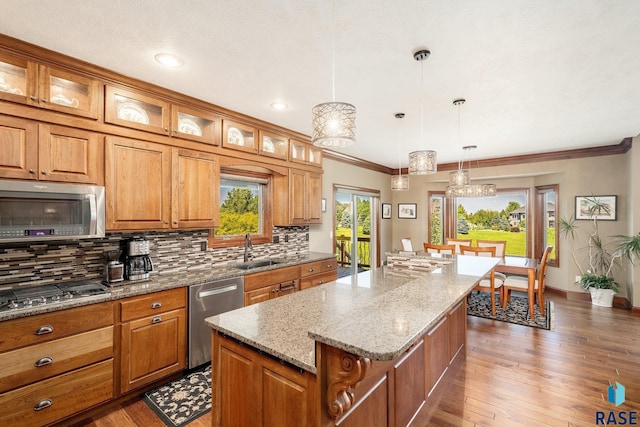 kitchen featuring sink, tasteful backsplash, appliances with stainless steel finishes, a kitchen island, and pendant lighting