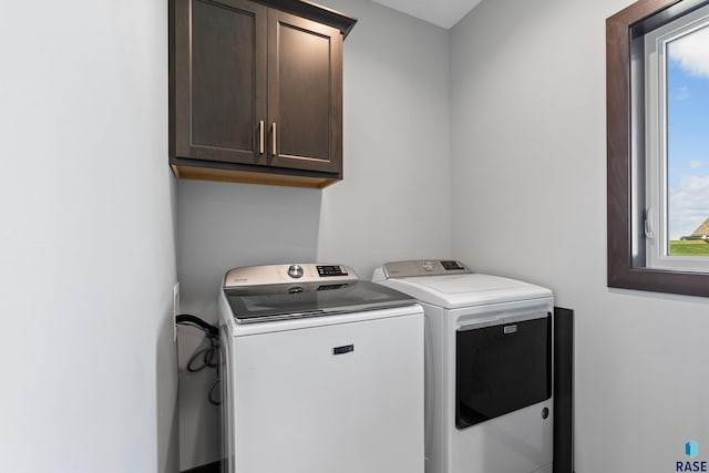 clothes washing area with washing machine and dryer and cabinet space