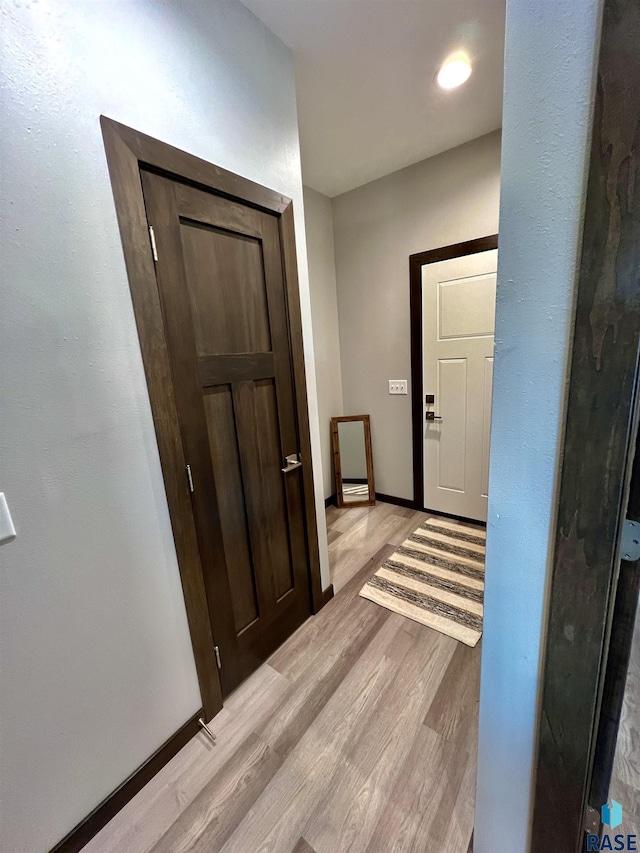 hall featuring light wood finished floors and baseboards