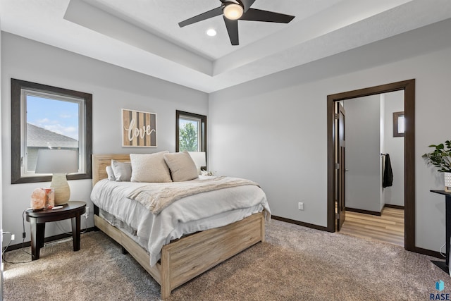 bedroom featuring recessed lighting, a raised ceiling, a ceiling fan, light carpet, and baseboards