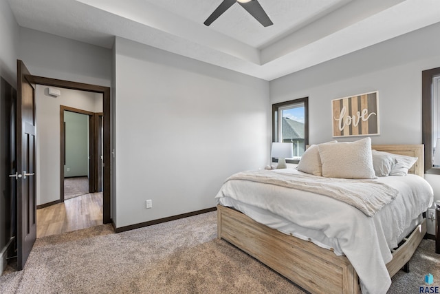carpeted bedroom with baseboards, a ceiling fan, and a raised ceiling