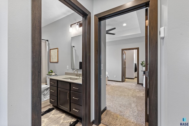 bathroom featuring a raised ceiling, baseboards, toilet, and vanity
