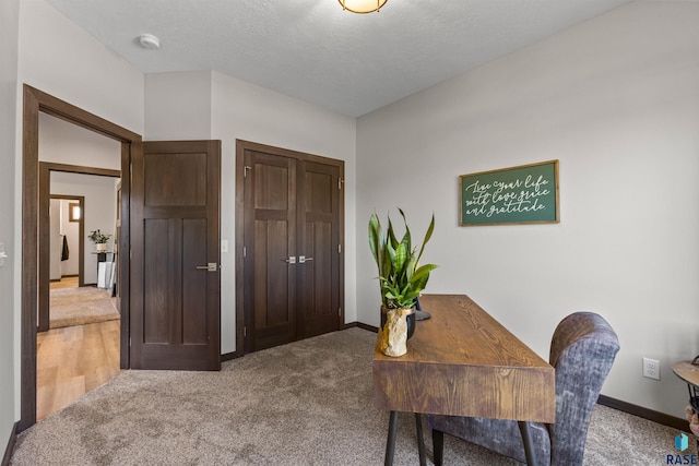 home office featuring baseboards, a textured ceiling, and light colored carpet