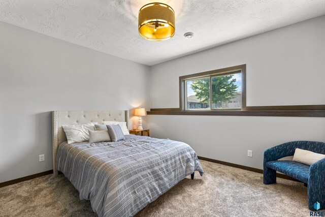 carpeted bedroom with a textured ceiling and baseboards
