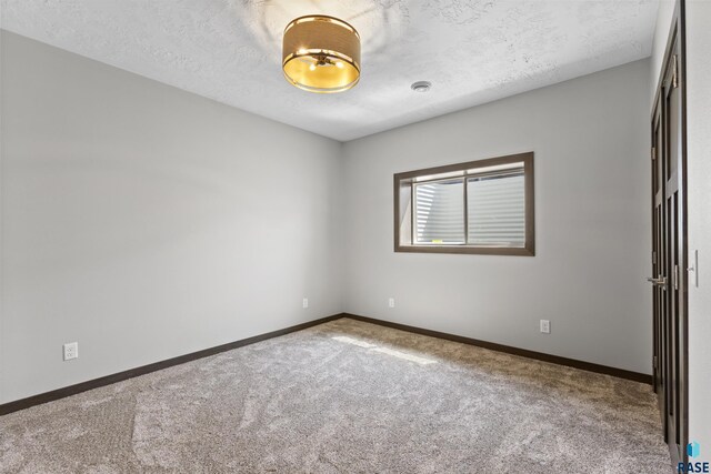 carpeted empty room featuring baseboards and a textured ceiling