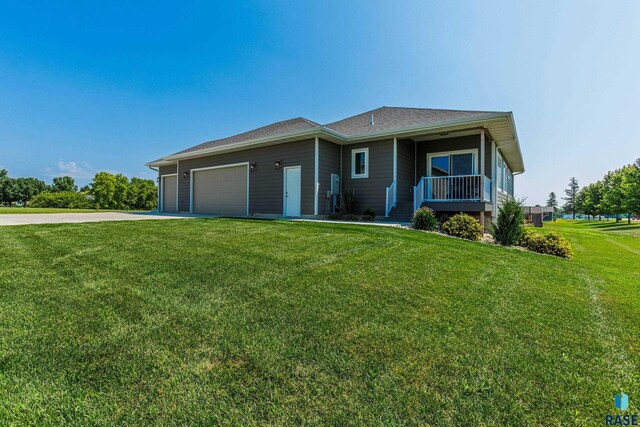 view of front of property featuring driveway, a front yard, covered porch, and a garage