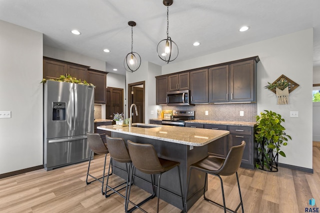 kitchen with baseboards, dark brown cabinets, stainless steel appliances, and a sink