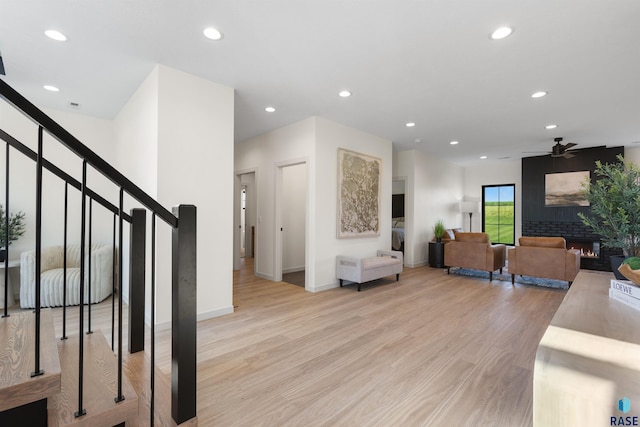 living room with recessed lighting, light wood-style floors, baseboards, a glass covered fireplace, and ceiling fan