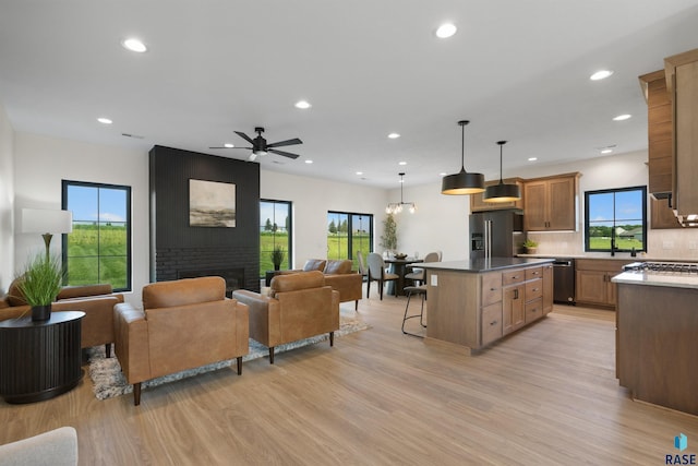 interior space with a kitchen breakfast bar, a kitchen island, light wood-style flooring, appliances with stainless steel finishes, and open floor plan