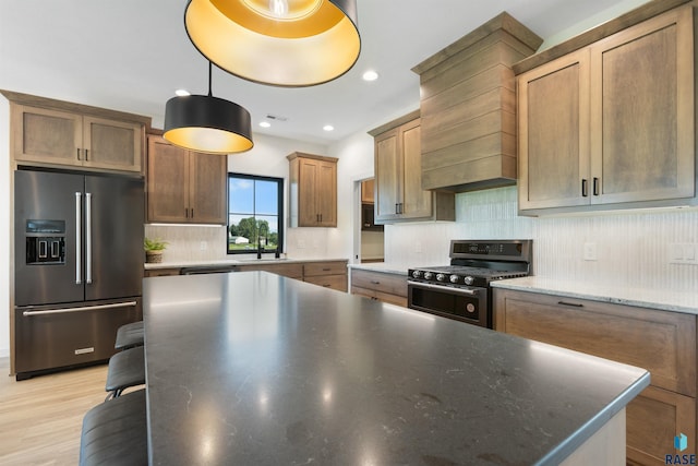 kitchen with stainless steel appliances, a sink, custom exhaust hood, decorative backsplash, and a kitchen island