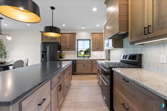 kitchen with backsplash, high end black fridge, gas range, light wood-style flooring, and custom exhaust hood