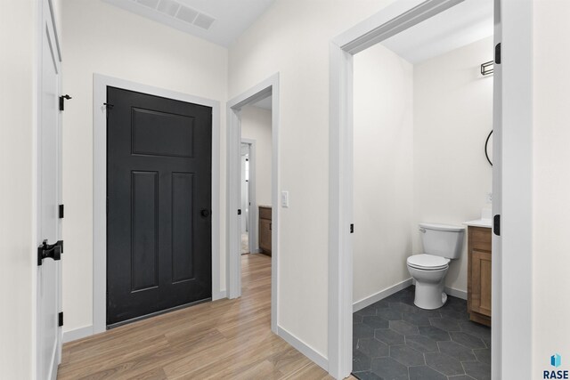 interior space featuring wood finished floors, vanity, baseboards, toilet, and visible vents