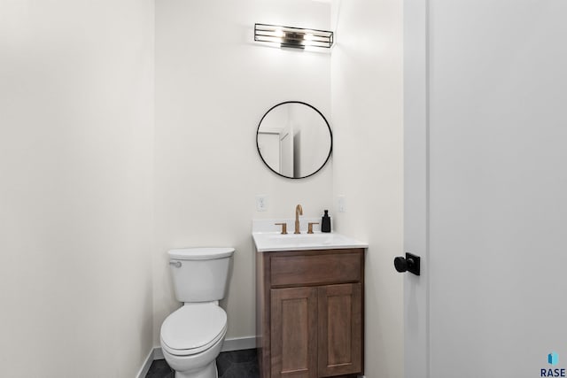 bathroom with toilet, vanity, and baseboards