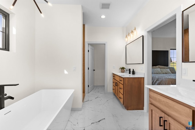bathroom featuring marble finish floor, visible vents, ensuite bath, two vanities, and a freestanding tub