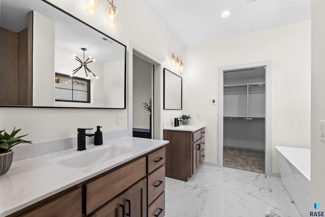 bathroom with two vanities, a sink, a freestanding bath, baseboards, and marble finish floor