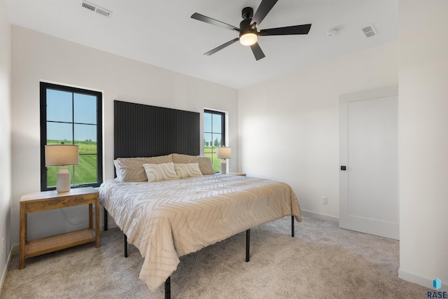 carpeted bedroom with baseboards, a ceiling fan, and visible vents