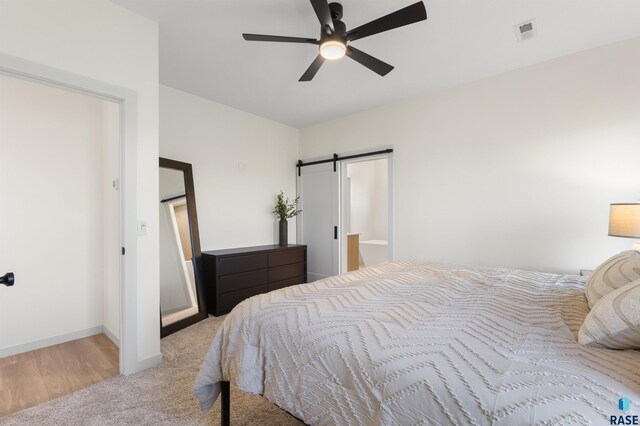 bedroom with a barn door, baseboards, visible vents, carpet, and ceiling fan