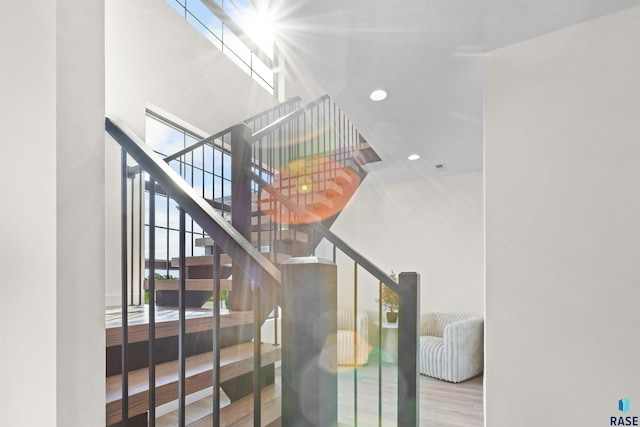 staircase featuring recessed lighting, wood finished floors, and a towering ceiling