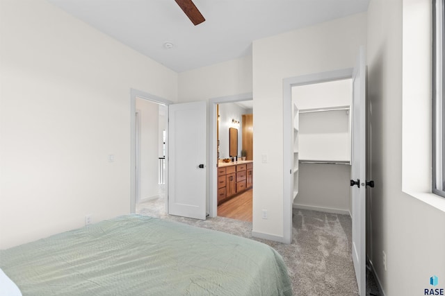 bedroom featuring a spacious closet, a ceiling fan, light carpet, ensuite bath, and a closet