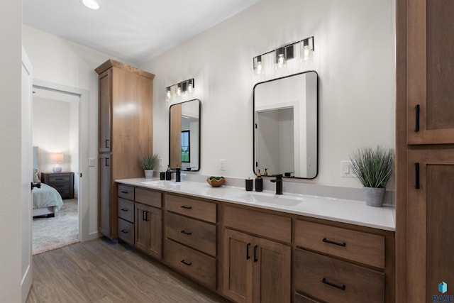 ensuite bathroom featuring ensuite bathroom, wood finished floors, a sink, and double vanity