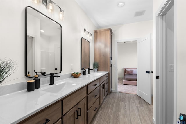 full bathroom featuring double vanity, wood finished floors, visible vents, and a sink