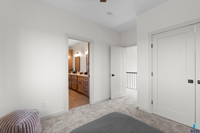 unfurnished bedroom featuring ensuite bathroom, baseboards, a closet, and light colored carpet