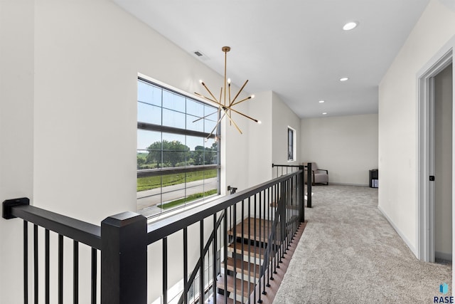 corridor with an upstairs landing, carpet floors, a notable chandelier, visible vents, and recessed lighting