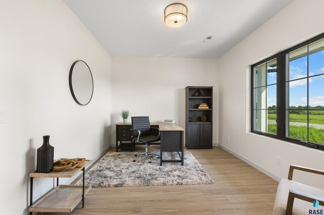 office space with baseboards, wood finished floors, and visible vents