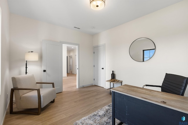 home office with baseboards, light wood finished floors, and visible vents