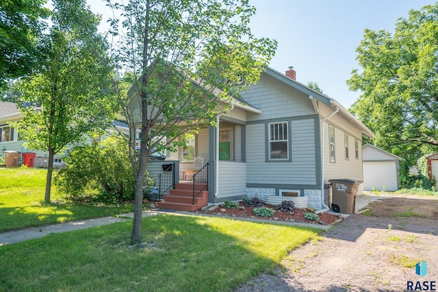 view of front of home featuring an outdoor structure, a garage, covered porch, and a front lawn