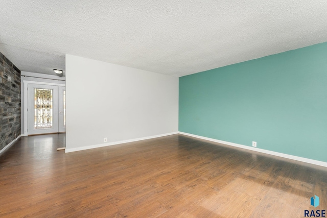 unfurnished room with dark wood-type flooring and a textured ceiling