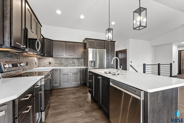 kitchen featuring dark hardwood / wood-style floors, a kitchen island with sink, sink, stainless steel appliances, and decorative light fixtures