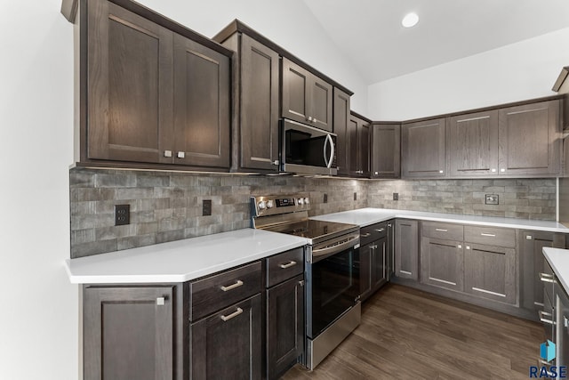 kitchen featuring dark brown cabinetry, lofted ceiling, appliances with stainless steel finishes, dark hardwood / wood-style floors, and decorative backsplash