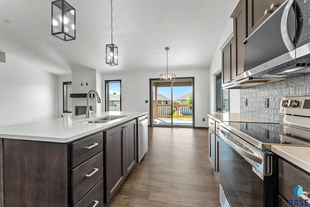 kitchen featuring pendant lighting, sink, a kitchen island with sink, appliances with stainless steel finishes, and dark hardwood / wood-style floors