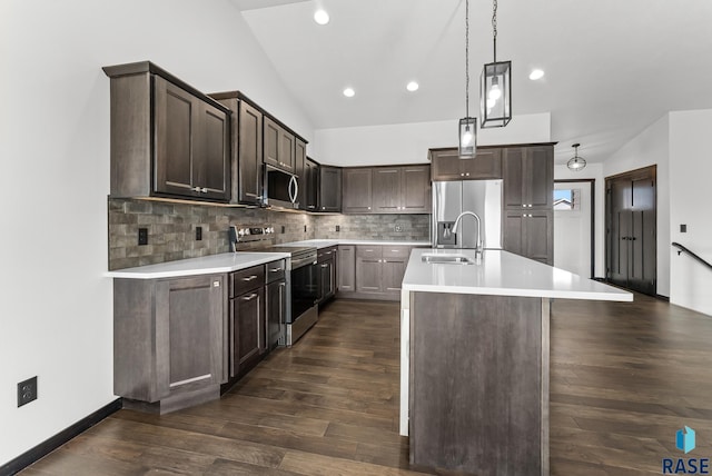 kitchen featuring sink, a center island with sink, appliances with stainless steel finishes, dark hardwood / wood-style floors, and vaulted ceiling