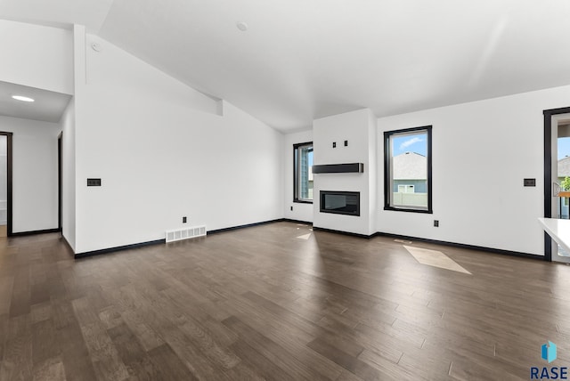 unfurnished living room featuring vaulted ceiling and dark hardwood / wood-style flooring