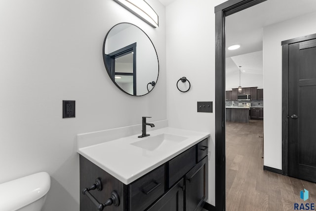 bathroom with wood-type flooring, vanity, and toilet